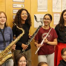 three students holding new instruments and their band teacher 