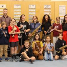 Group of students holding new instruments alongside two adults